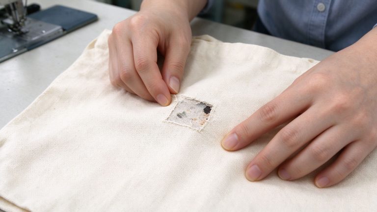 Close-up inspection of canvas tote bag fabric weave and visible surface defects
