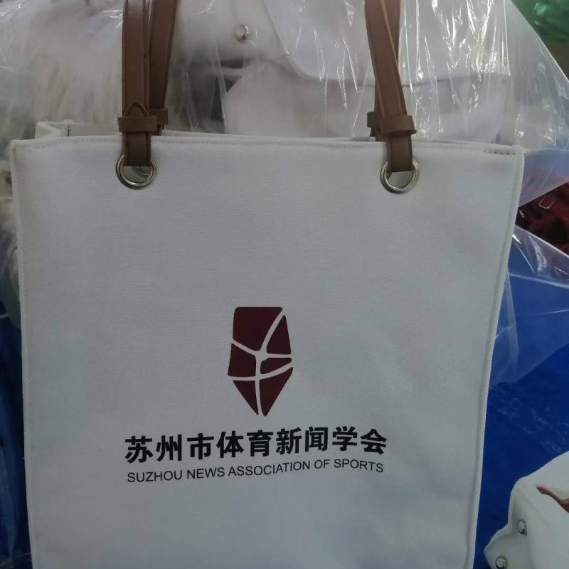 White canvas tote bag with brown PU leather handles and metal grommets
